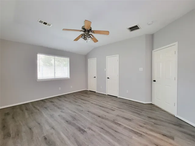 a view of empty room with wooden floor and fan