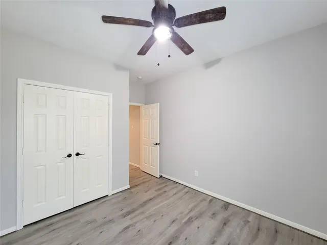 an empty room with wooden floor ceiling fan and window