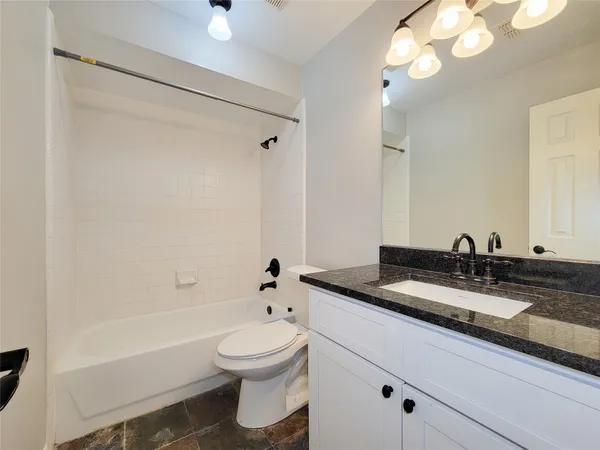 a bathroom with a granite countertop sink a toilet and shower