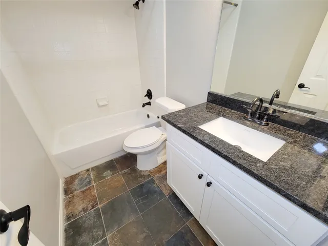 a bathroom with a granite countertop sink mirror vanity and toilet