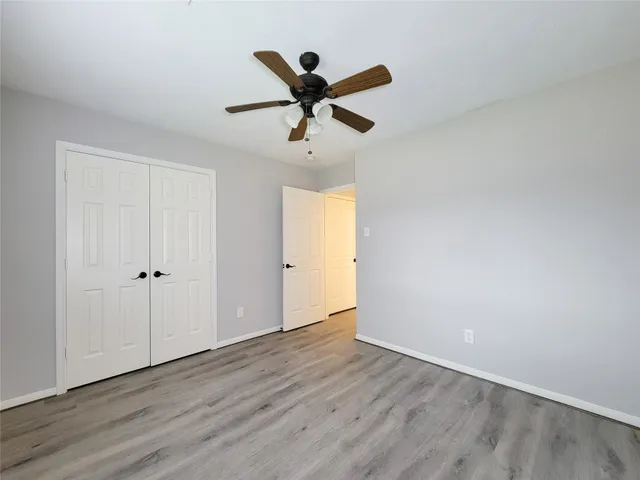 an empty room with wooden floor and ceiling fan