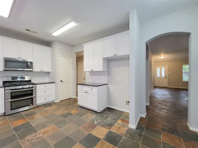 a kitchen with stainless steel appliances granite countertop a refrigerator and a stove top oven