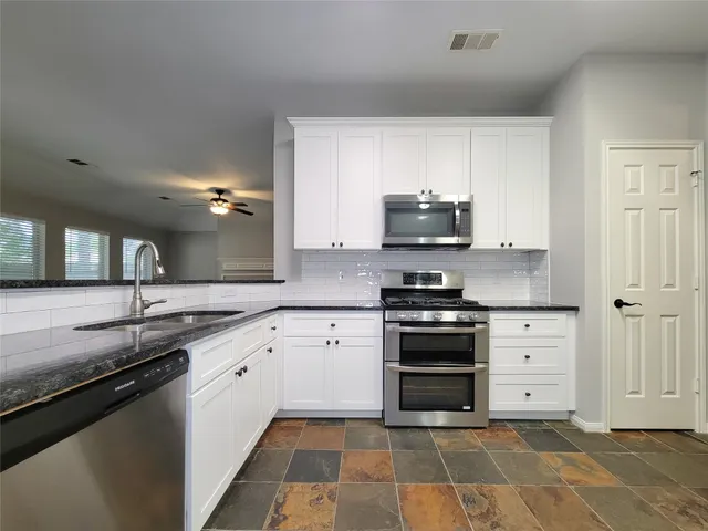 a kitchen with stainless steel appliances granite countertop a sink and a stove