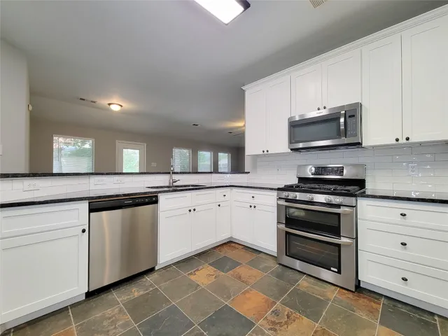a kitchen with stainless steel appliances granite countertop a stove a sink and a microwave
