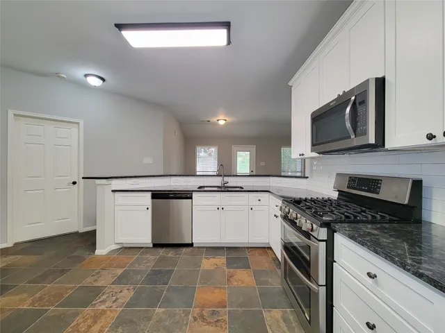 a kitchen with stainless steel appliances granite countertop a stove a sink and a microwave