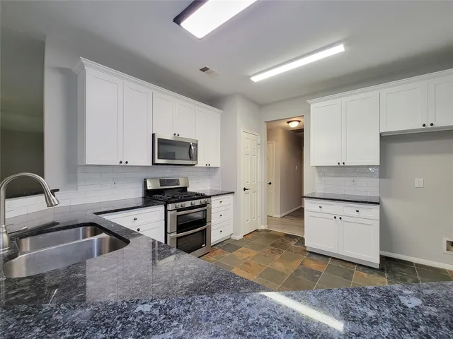 a kitchen with stainless steel appliances granite countertop a sink a stove top oven a counter space and cabinets