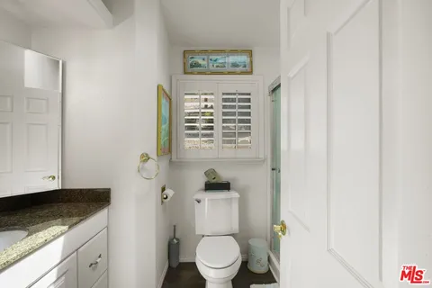 a bathroom with a granite countertop sink toilet and mirror