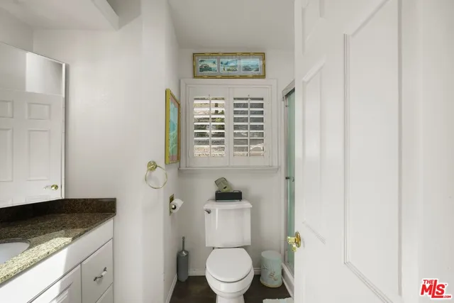a bathroom with a granite countertop sink toilet and mirror