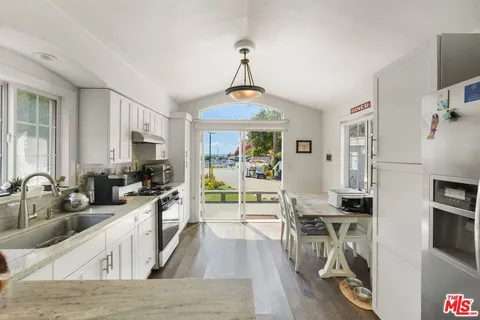 a kitchen with stainless steel appliances a stove top oven a sink a dining table and chairs