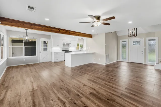 an empty room with wooden floor and windows