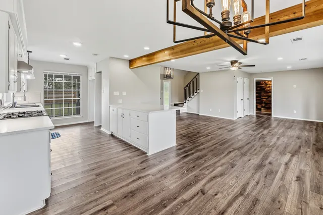 a view of an empty room with wooden floor and windows