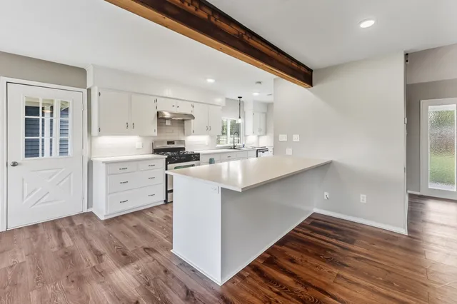 a large kitchen with stainless steel appliances a large counter top a sink a stove and a refrigerator