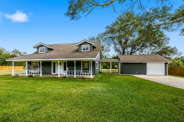 a view of a house with a big yard and large trees