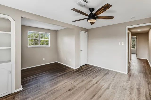 an empty room with wooden floor and a ceiling fan