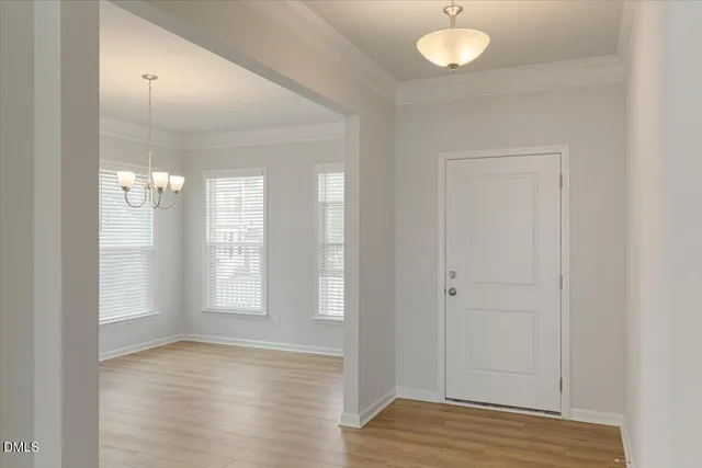 a view of an empty room with wooden floor and chandelier