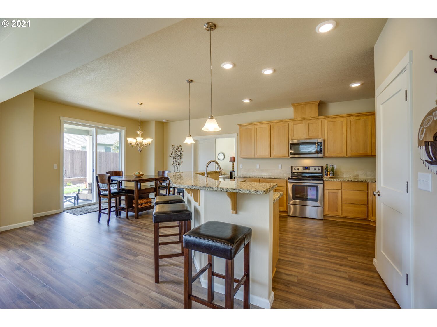 4639 North Noble Loop Ridgefield, WA 98642 - Photo 8 of 32 a kitchen with stainless steel appliances granite countertop a refrigerator a stove top oven and a dining table with wooden floor