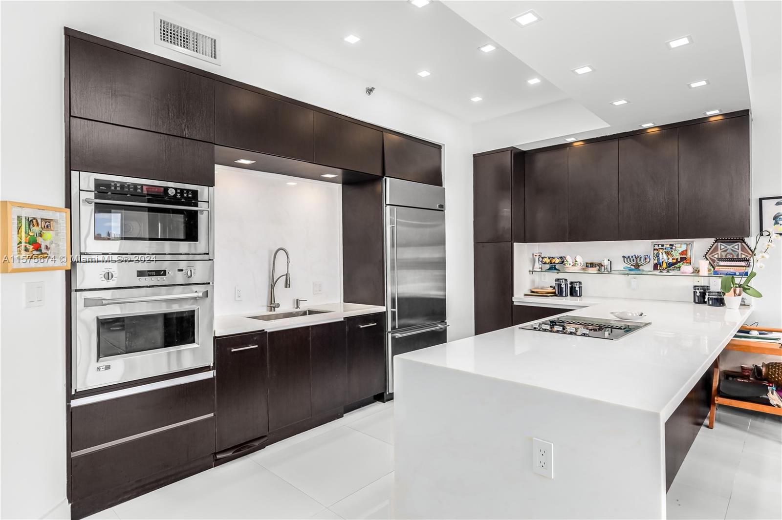 a kitchen with kitchen island stainless steel appliances a stove refrigerator sink and cabinets