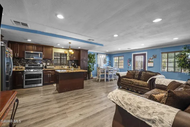 a living room with stainless steel appliances furniture and a kitchen view