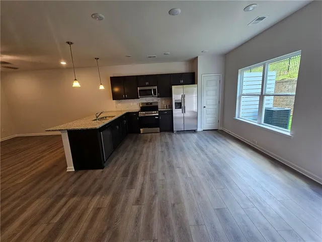 a kitchen with stainless steel appliances wooden floors and view living room