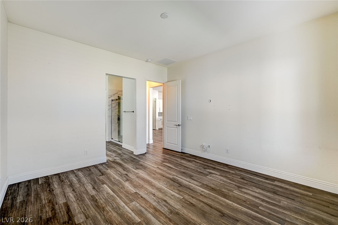 8197 Riley Love Street Las Vegas, NV 89139 - Photo 27 of 48 Hardwood-style flooring extends from the bedroom into an adjoining private bathroom.