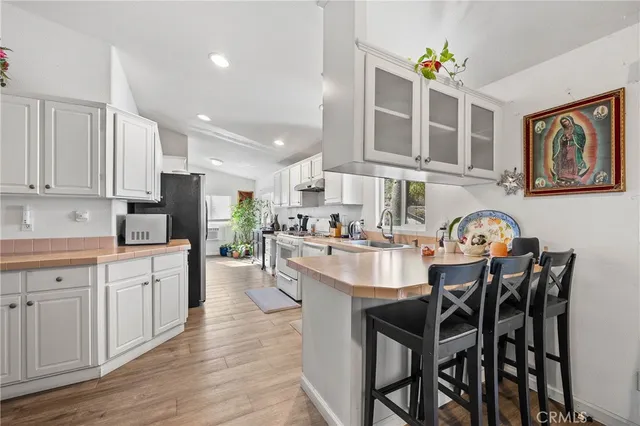 a kitchen with stainless steel appliances granite countertop a dining table chairs and white cabinets