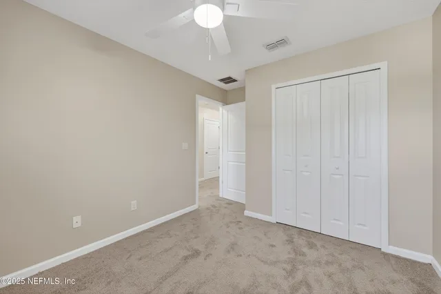 a view of a brick house with a yard plants and large tree
