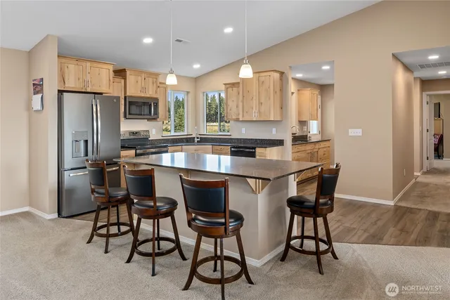 a kitchen with stainless steel appliances a dining table chairs refrigerator and microwave