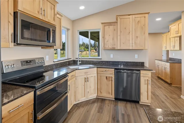 a kitchen with stainless steel appliances granite countertop wooden cabinets stove top oven and sink
