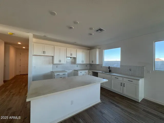 a large kitchen with a lot of counter space and wooden floor