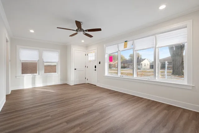 a view of an empty room with a window and wooden floor