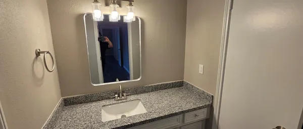 a bathroom with a granite countertop sink and a mirror