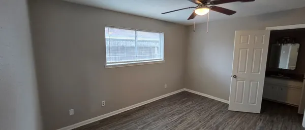 an empty room with wooden floor fan and windows