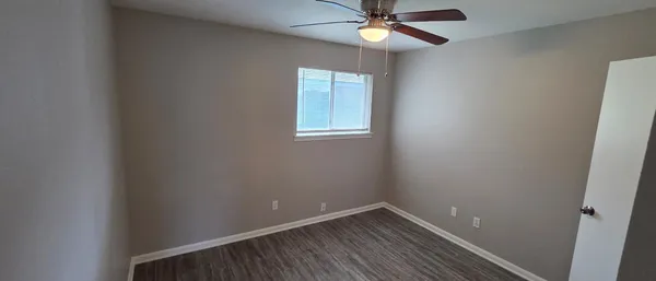 an empty room with a window and a fan