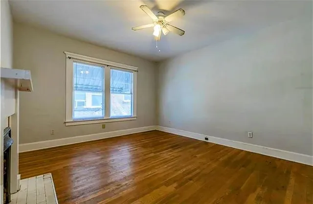 a view of an empty room with window and wooden floor
