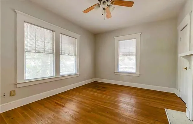 a view of an empty room with a window and wooden floor