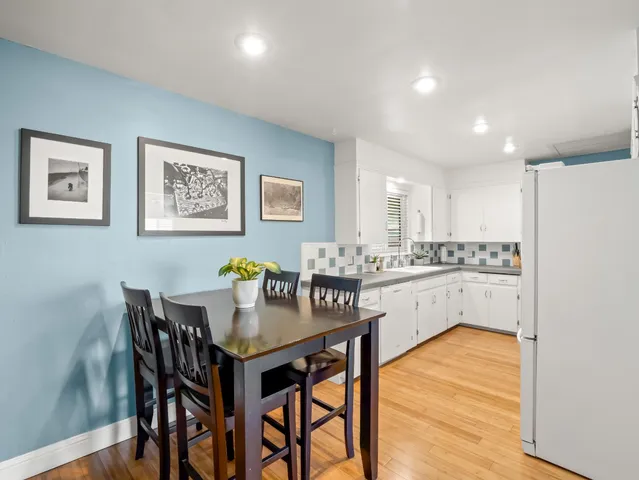 a kitchen with a dining table chairs and wooden floor