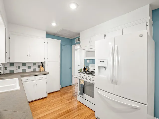 a kitchen with stainless steel appliances a stove a refrigerator and white cabinets