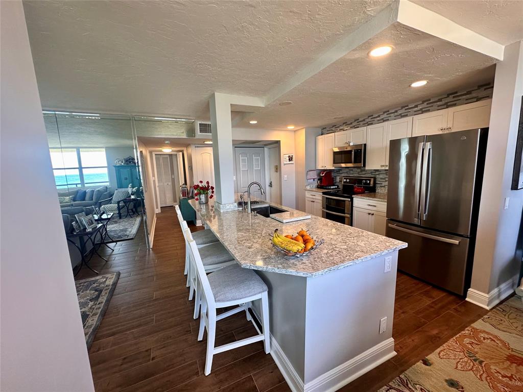 1147 Hillsboro Mile, Unit 214 Hillsboro Beach, FL 33062 - Photo 22 of 43 a kitchen with stainless steel appliances granite countertop a refrigerator a stove top oven a sink dishwasher and white cabinets with wooden floor