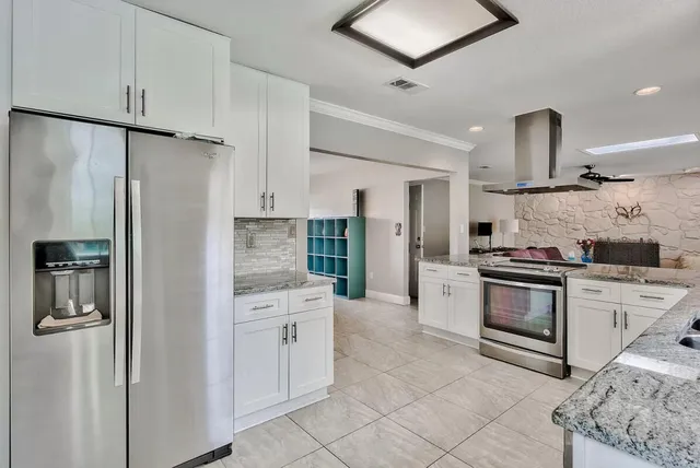 a kitchen with stainless steel appliances granite countertop a refrigerator a stove and a sink