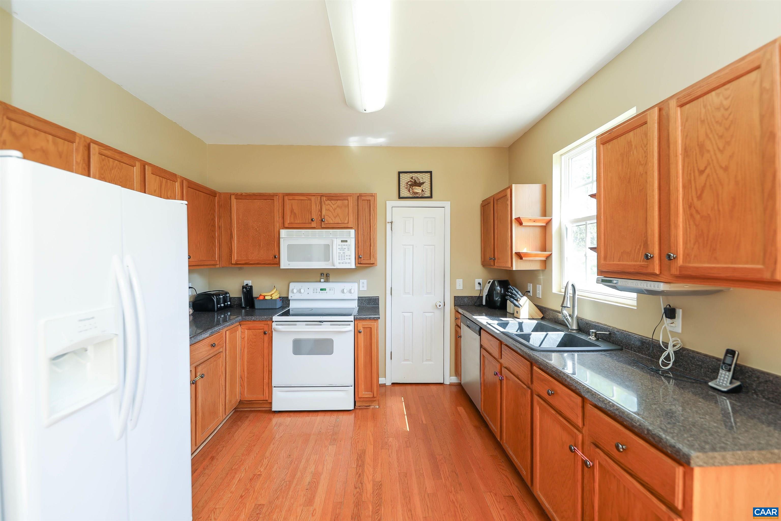 286 Snapdragon Road Ruckersville, VA 22968 - Photo 14 of 44 a kitchen with stainless steel appliances granite countertop a refrigerator a sink dishwasher a stove with wooden cabinets and floor