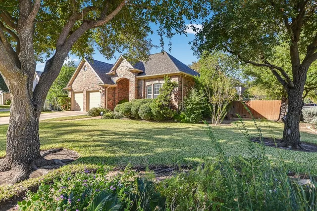 a front view of a house with a garden and trees