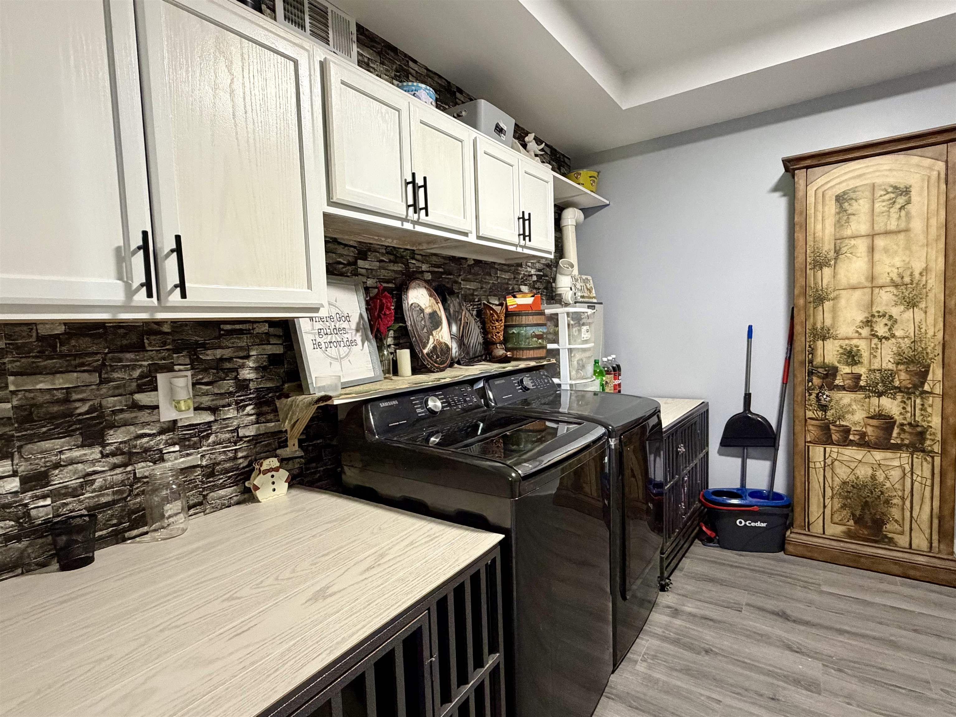 3670 Peavine Road Middleton, TN 38052 - Photo 14 of 36 Laundry area featuring a stone-look backsplash, white upper cabinetry with black hardware, wood-finish countertops, and wood-finish flooring