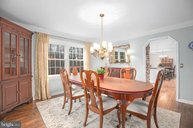 a dining room with wooden floor a chandelier a wooden table and chairs