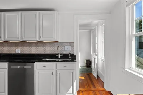 a kitchen with granite countertop a sink a stove and cabinets