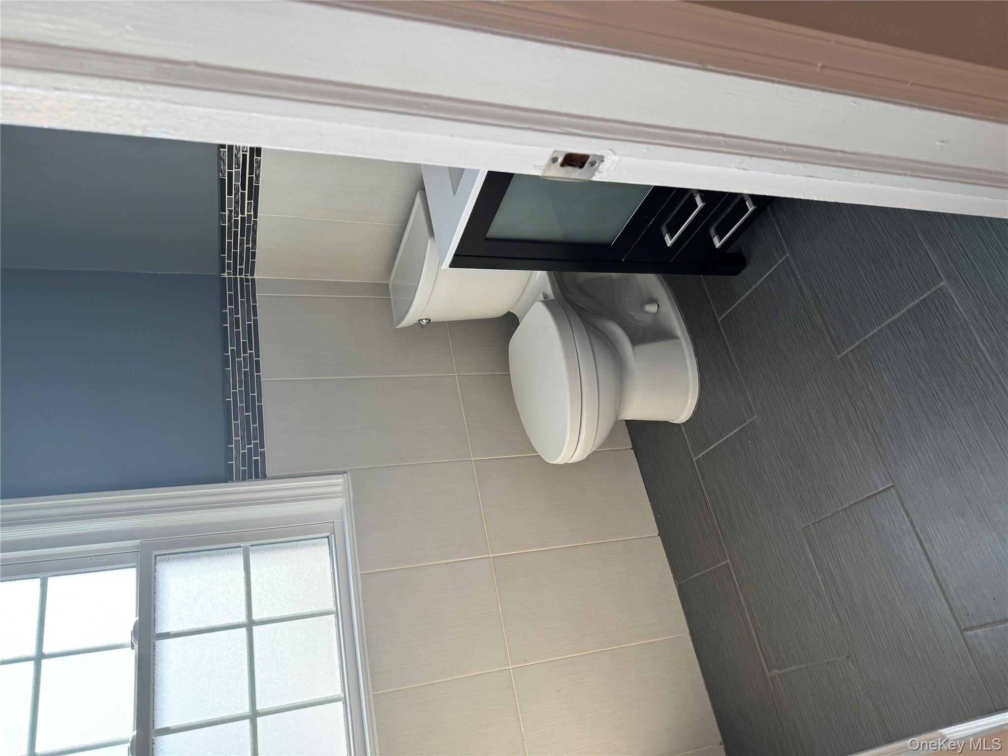 31 Flower Road Valley Stream, NY 11581 - Photo 13 of 16 Bathroom featuring dark tile patterned flooring, vanity, and tile walls