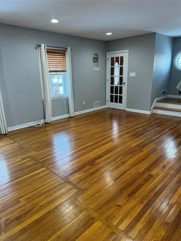 a view of empty room with window and wooden floor