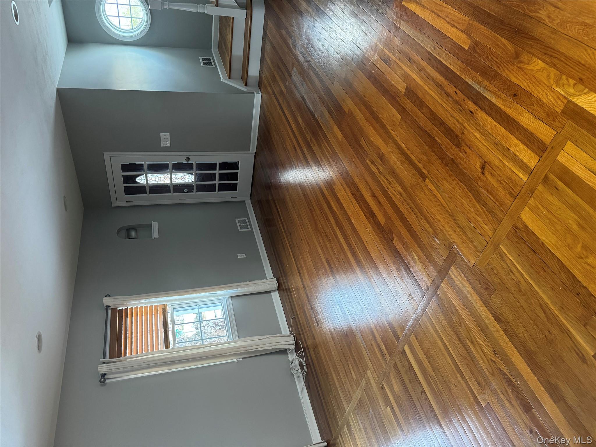 31 Flower Road Valley Stream, NY 11581 - Photo 4 of 16 Unfurnished living room featuring plenty of natural light, hardwood / wood-style floors, and stairway