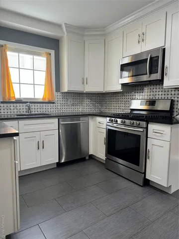a kitchen with granite countertop white cabinets stainless steel appliances and window