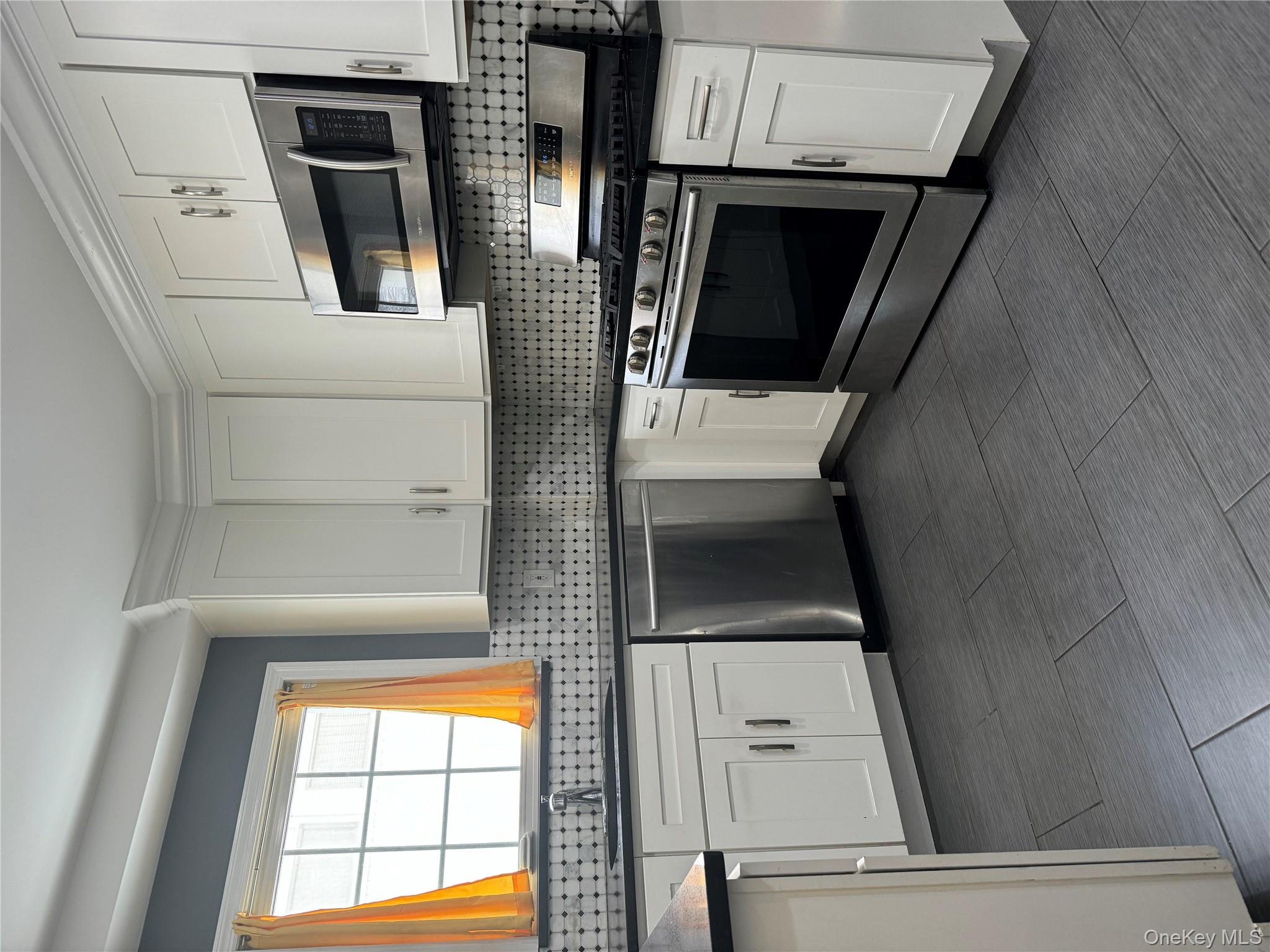 31 Flower Road Valley Stream, NY 11581 - Photo 7 of 16 Kitchen featuring appliances with stainless steel finishes, white cabinetry, and tasteful backsplash