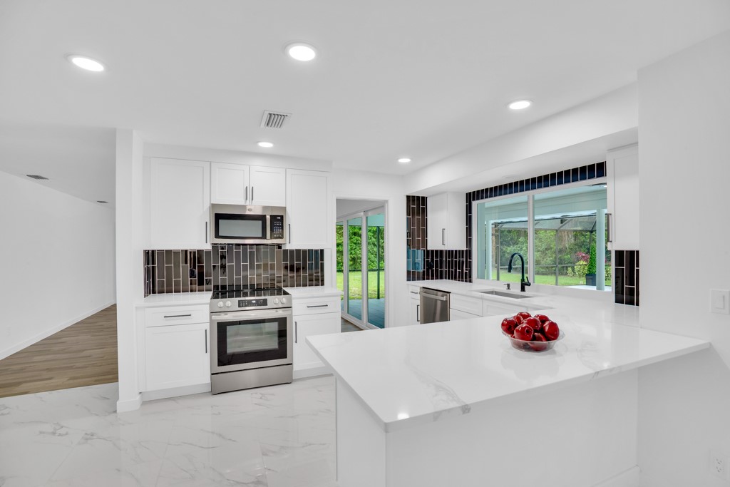 4384 2nd Square Southwest Vero Beach, FL 32968 - Photo 11 of 36 a kitchen with a sink dishwasher a stove and white cabinets with wooden floor